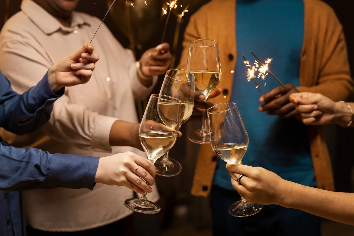 Amigos fazendo um brinde com taças e estrelinhas acesas em festa de fim de ano